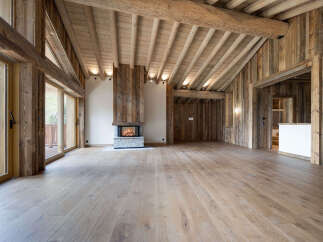Experience rustic luxury in this stunning mountain chalet featuring a grand living space with a stone fireplace and exposed wooden beams.