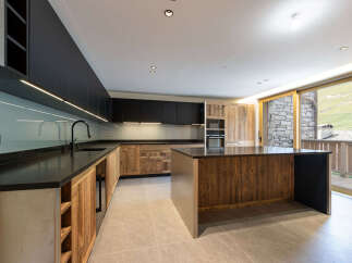 Experience modern mountain living in this stunning kitchen, featuring sleek black cabinetry contrasted with warm, rustic wood accents.