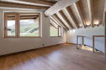 Experience breathtaking mountain views from this stunning attic room, featuring a rustic wooden beamed ceiling and expansive windows.