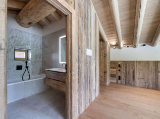 Experience rustic luxury in this stunning bathroom featuring a deep soaking tub and a modern vanity with a backlit mirror.