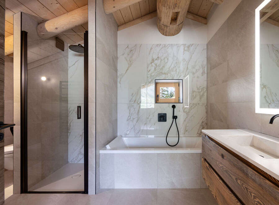 Experience luxury mountain living in this stunning bathroom featuring a spacious walk-in shower with a rainfall showerhead and a deep soaking tub.