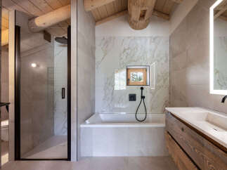 Experience luxury mountain living in this stunning bathroom featuring a spacious walk-in shower with a rainfall showerhead and a deep soaking tub.