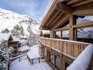 Experience the ultimate alpine retreat in this stunning wooden chalet, nestled amidst snow-covered mountains and evergreen trees.