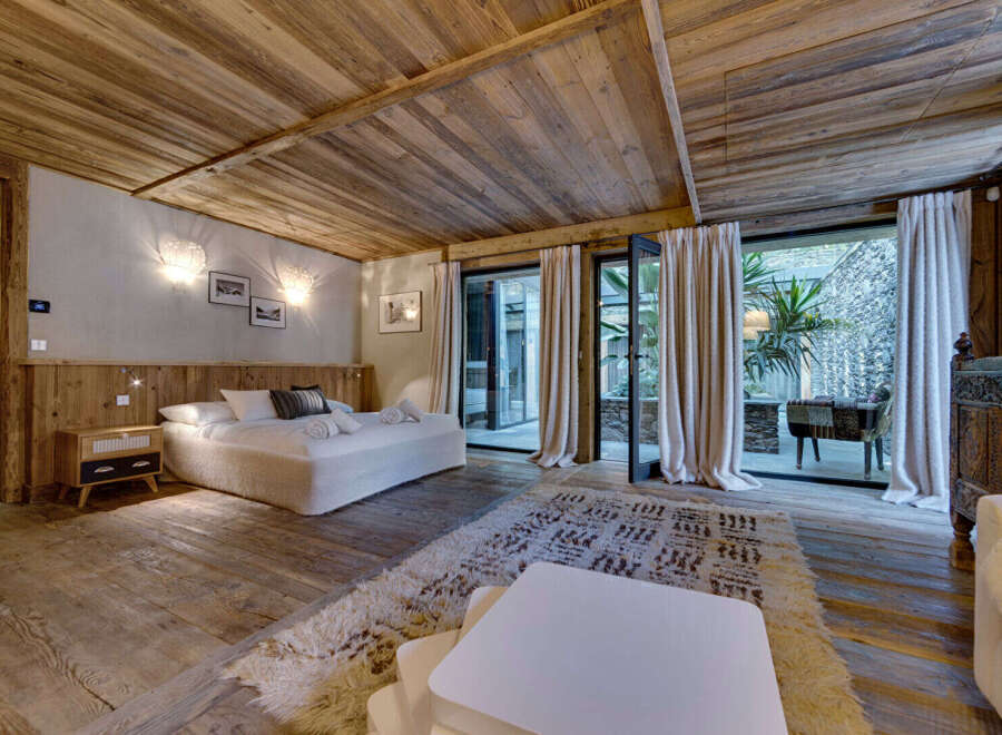 This luxurious bedroom boasts a rustic charm with its wooden ceiling, floors, and headboard.
