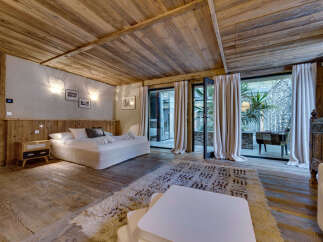 This luxurious bedroom boasts a rustic charm with its wooden ceiling, floors, and headboard.