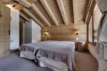 This cozy bedroom features a rustic design with wooden walls and ceiling beams, creating a warm and inviting atmosphere.