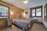 Discover the charm of this cozy bedroom, featuring a rustic wooden wall and elegant twin beds.