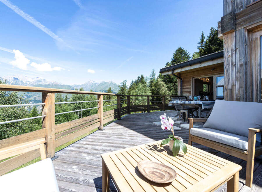 Enjoy breathtaking mountain views from this stunning wooden deck, perfect for al fresco dining or relaxing with a book.