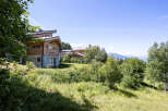 Experience breathtaking mountain views from this stunning wooden chalet, nestled amidst lush greenery.