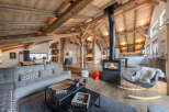 Experience rustic luxury in this stunning mountain chalet living room, featuring exposed wooden beams and a modern fireplace.