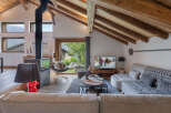 Experience cozy mountain living in this charming chalet featuring a striking black wood-burning stove and exposed wooden beams.