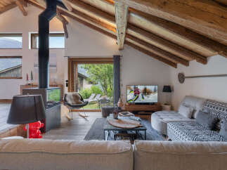 Experience cozy mountain living in this charming chalet featuring a striking black wood-burning stove and exposed wooden beams.