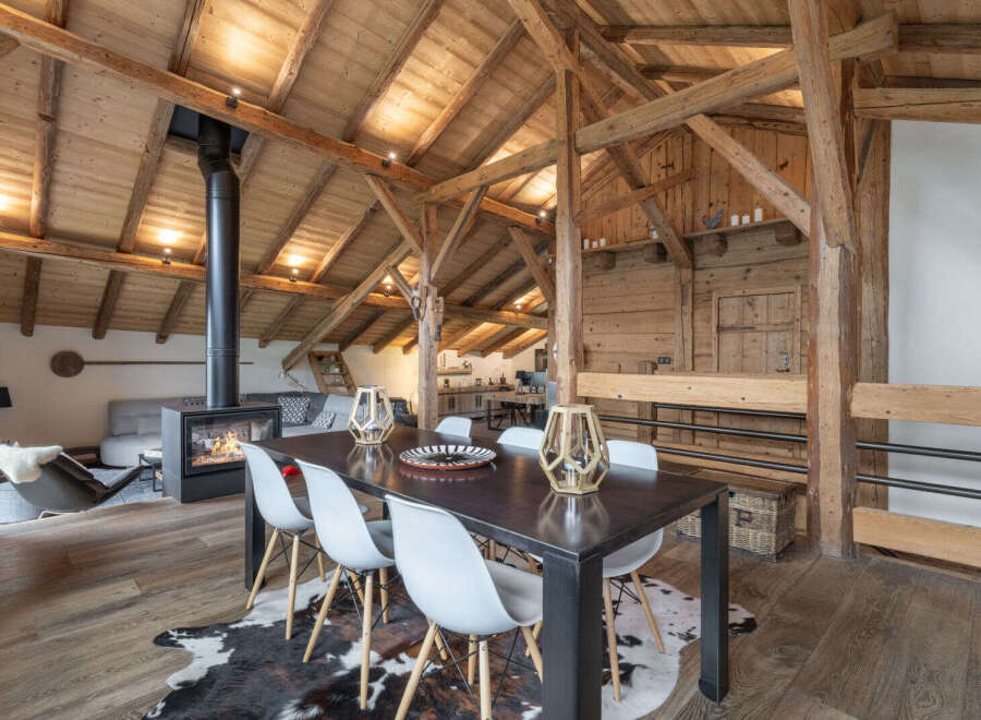 Experience rustic charm in this stunning open-plan living space, featuring exposed wooden beams and a cozy fireplace.