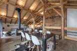 Experience rustic charm in this stunning open-plan living space, featuring exposed wooden beams and a cozy fireplace.