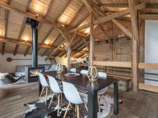 Experience rustic charm in this stunning open-plan living space, featuring exposed wooden beams and a cozy fireplace.