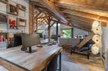 Experience rustic charm and modern comfort in this stunning attic living space, featuring exposed wooden beams and a cozy work area.