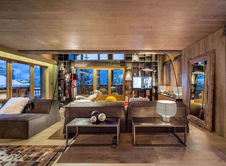 Experience luxury living in this stunning chalet, boasting a cozy living room with a fireplace and large windows offering breathtaking mountain views.