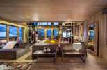 Experience luxury living in this stunning chalet, boasting a cozy living room with a fireplace and large windows offering breathtaking mountain views.