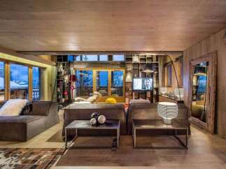 Experience luxury living in this stunning chalet, boasting a cozy living room with a fireplace and large windows offering breathtaking mountain views.