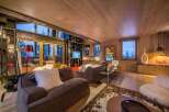 Experience luxury living in this stunning chalet, featuring a cozy living room with a fireplace and large windows offering breathtaking mountain views.