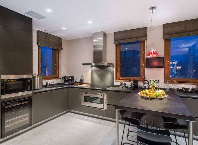 This modern kitchen boasts sleek, dark cabinetry and stainless steel appliances, creating a sophisticated and functional space.