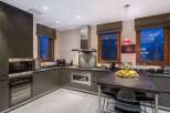 This modern kitchen boasts sleek, dark cabinetry and stainless steel appliances, creating a sophisticated and functional space.