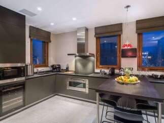 This modern kitchen boasts sleek, dark cabinetry and stainless steel appliances, creating a sophisticated and functional space.