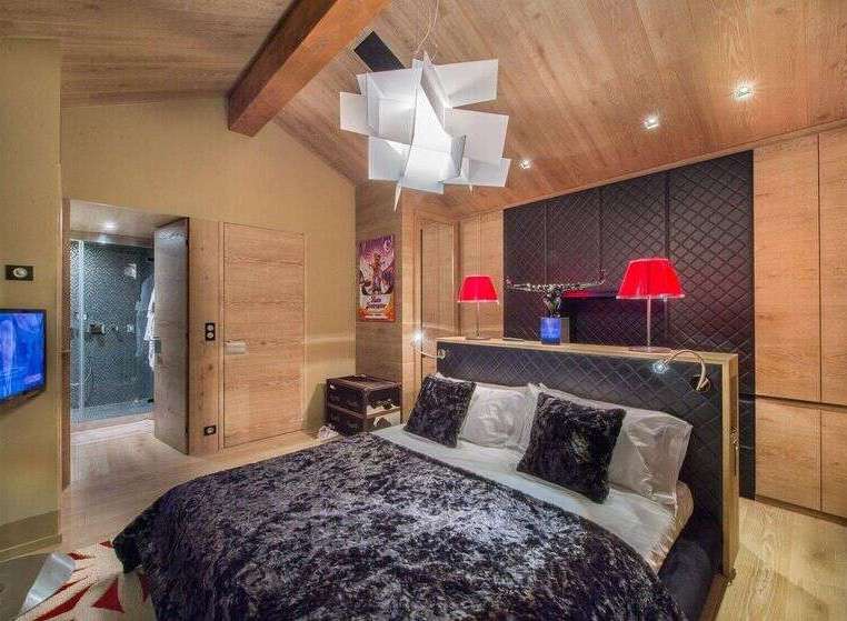 Experience luxury in this stunning bedroom featuring a plush velvet bedspread and a unique geometric chandelier.