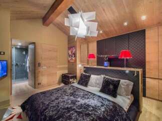 Experience luxury in this stunning bedroom featuring a plush velvet bedspread and a unique geometric chandelier.