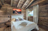 Experience the rustic charm of this cozy bedroom, featuring stunning wood paneling and a vaulted ceiling.