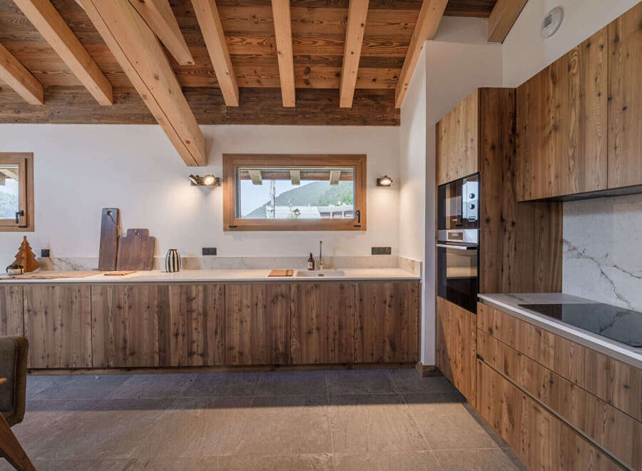 Experience the warmth and elegance of this stunning kitchen, featuring custom wooden cabinetry and a beautiful stone countertop.