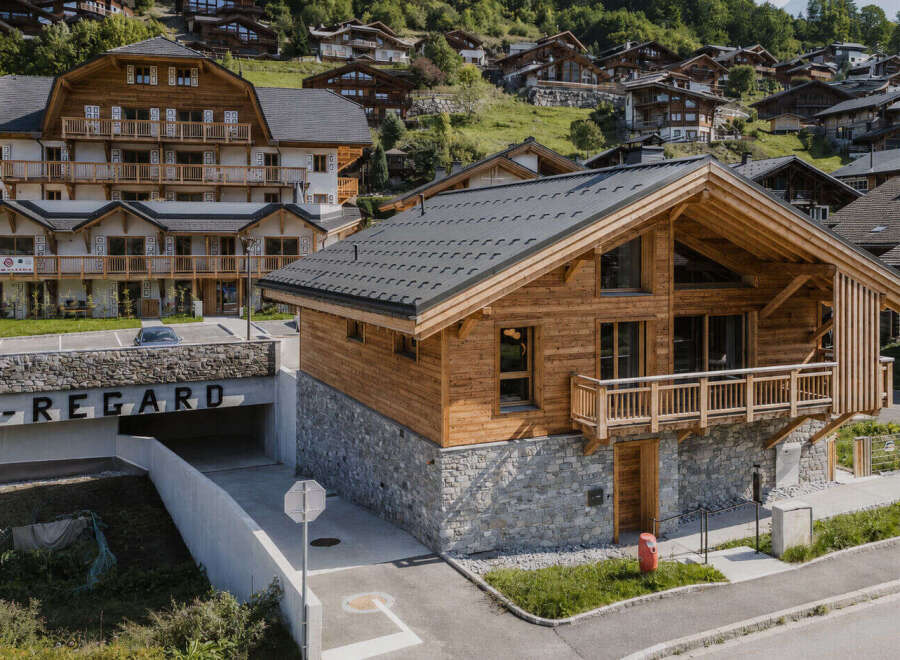Experience luxury mountain living in this stunning chalet, featuring a rustic wooden exterior complemented by a stone base.