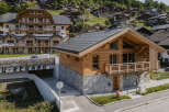 Experience luxury mountain living in this stunning chalet, featuring a rustic wooden exterior complemented by a stone base.