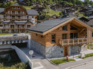 Experience luxury mountain living in this stunning chalet, featuring a rustic wooden exterior complemented by a stone base.