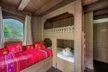 This cozy bedroom features custom-built bunk beds and a window seat, perfect for a mountain retreat.