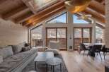 Experience luxury living in this stunning chalet, featuring a spacious living area with a cozy sofa and a modern dining space.