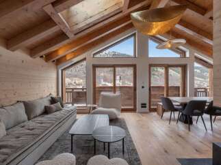 Experience luxury living in this stunning chalet, featuring a spacious living area with a cozy sofa and a modern dining space.
