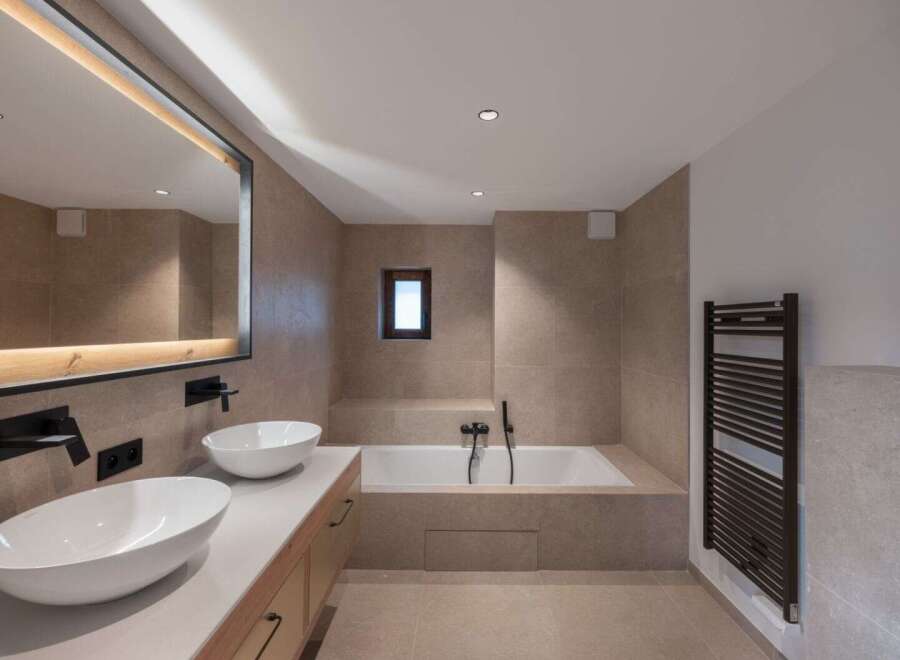 This modern bathroom features a sleek design with a soaking tub and a double vanity.