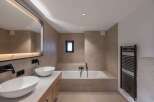 This modern bathroom features a sleek design with a soaking tub and a double vanity.