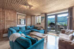 Experience the charm of this cozy living space, featuring a stylish teal sectional sofa and a rustic wooden ceiling.