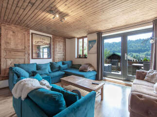 Experience the charm of this cozy living space, featuring a stylish teal sectional sofa and a rustic wooden ceiling.