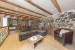 This charming property boasts a cozy living space with a stone wall and wooden beams, creating a rustic and inviting atmosphere.