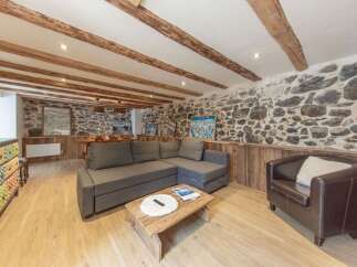 This charming property boasts a cozy living space with a stone wall and wooden beams, creating a rustic and inviting atmosphere.