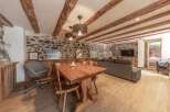 Experience rustic charm in this stunning property featuring exposed wooden beams and a stone wall.