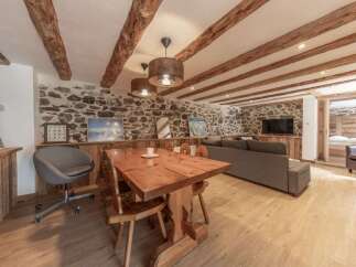 Experience rustic charm in this stunning property featuring exposed wooden beams and a stone wall.