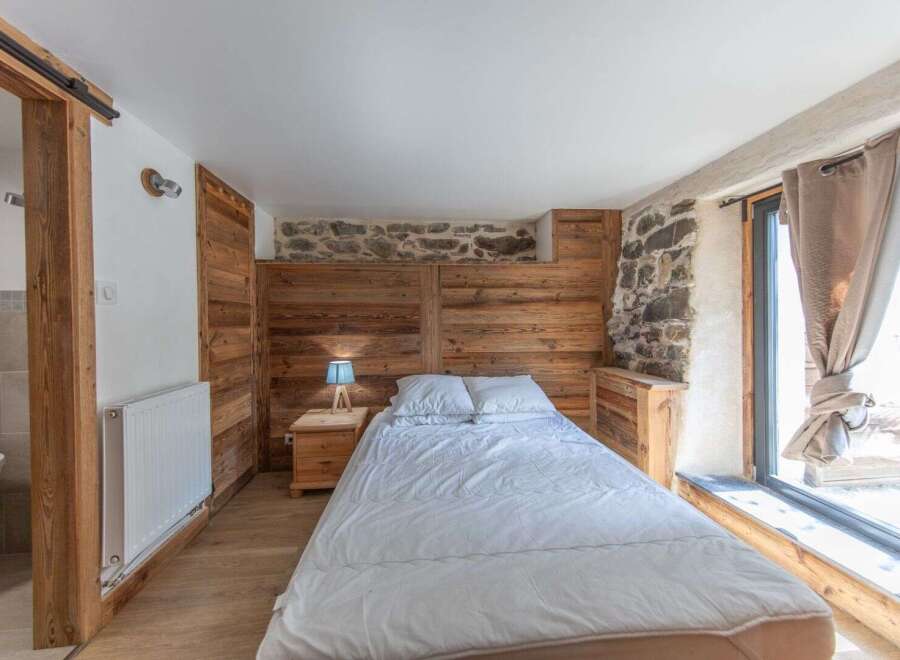 This cozy bedroom features a rustic design with wooden paneling and a stone accent wall, creating a warm and inviting atmosphere.