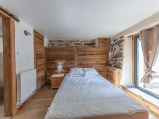 This cozy bedroom features a rustic design with wooden paneling and a stone accent wall, creating a warm and inviting atmosphere.