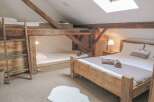 Discover the charm of this unique bedroom featuring rustic wooden beams and a cozy bunk bed setup, perfect for a family getaway.