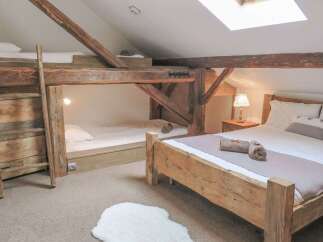 Discover the charm of this unique bedroom featuring rustic wooden beams and a cozy bunk bed setup, perfect for a family getaway.