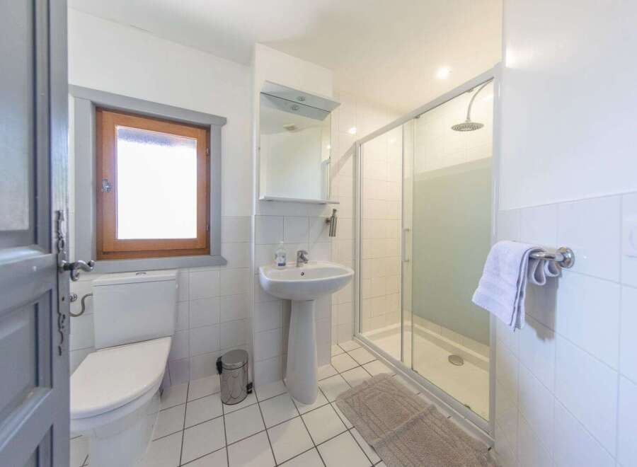 This bright and airy bathroom features a modern shower, a pedestal sink, and a toilet.